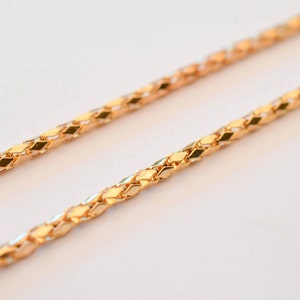 Puede incluir: Un collar de cadena de oro con un diseño trenzado delicado. La cadena está hecha de pequeños diamantes unidos.