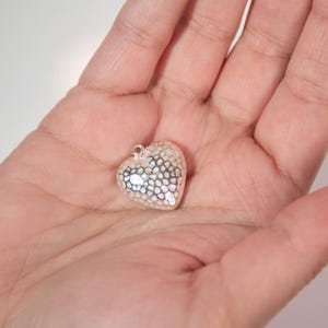 May include: A silver heart-shaped pendant with a textured surface.