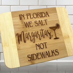 May include: A wooden cutting board with the text "In Florida we salt margaritas, not sidewalks" and a margarita glass with a lime slice.