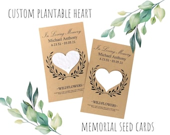 May include: Two brown plantable seed cards with a heart-shaped cutout. The cards feature the text "In Loving Memory" and a name and dates. The text "WILDFLOWERS" is printed below the heart cutout. The cards are on a white background with green leaves.