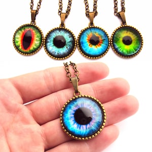 May include: Five necklaces with bronze chains and round pendants featuring colorful eye designs. The pendants have a black pupil and a gold rim.