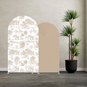 Può includere: Due pannelli di sfondo ad arco. Uno presenta una scena safari con elefanti, giraffe e mongolfiere in marrone su sfondo bianco. L'altro è un pannello beige con linee verticali. Una pianta in vaso è a destra.