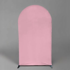 May include: A tall, arched backdrop stand covered in a smooth, solid light pink fabric cover. The structure features a rounded top edge and straight vertical sides, creating a clean, uniform surface that extends down to the base feet.