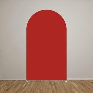 May include: A solid red arch-shaped backdrop cover featuring a smooth, matte fabric surface. The structure has a rounded top and straight vertical sides, supported by a thin metal frame base visible at the bottom, creating a clean, uniform display.