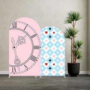 May include: Two arched backdrop stands. One is pink with a black clock face design. The other is light blue with a white diamond pattern and red and black card suit symbols. A potted plant is in the background.