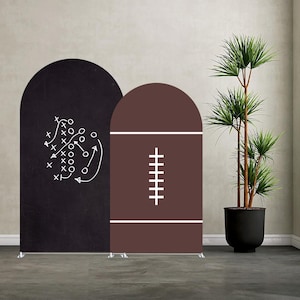 Könnte beinhalten: Zwei bogenförmige Hintergrundpaneele. Eines ist schwarz mit einem weißen Football-Spiel-Diagramm. Das andere ist braun mit einem weißen Football-Design. Die Paneele stehen auf einem grauen Boden mit einer hohen Topfpflanze im Hintergrund.