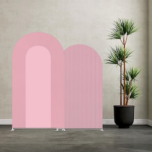 May include: A pink arched backdrop with a ribbed texture on one side and a smooth surface on the other. The backdrop is supported by a silver metal frame. A potted plant with green leaves is in the background.