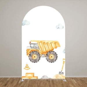 May include: A large, yellow watercolor dump truck is the focal point of this design, set against a white backdrop. The truck features gray wheels and is accompanied by a traffic cone, shovel, and clouds. The design is set on a white arch.