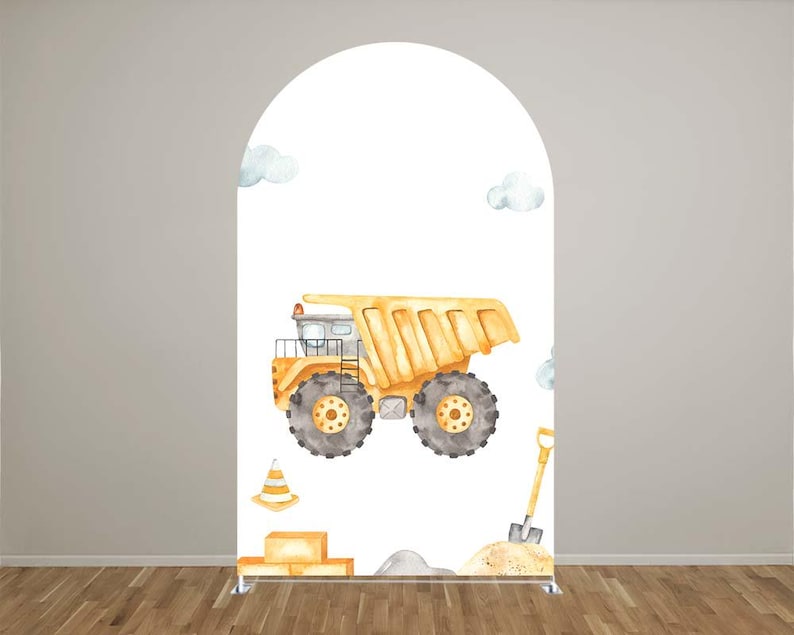 May include: A large, yellow watercolor dump truck is the focal point of this design, set against a white backdrop. The truck features gray wheels and is accompanied by a traffic cone, shovel, and clouds. The design is set on a white arch.