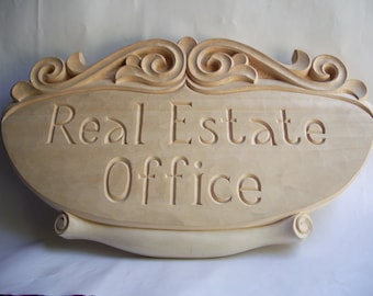 Puede incluir: Un letrero de madera con tallas ornamentadas y el texto "Real Estate Office" tallado en la superficie.