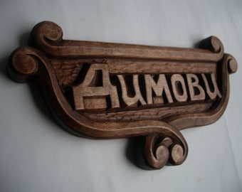 Puede incluir: Un letrero de madera marrón oscuro con la palabra "AUTOMOBIL" tallada en él. El letrero tiene un diseño decorativo de desplazamiento en cada extremo.