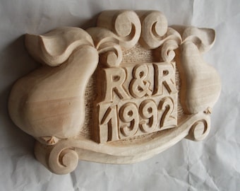 Puede incluir: Una placa de madera tallada con dos peras a cada lado del texto "R&R 1992".