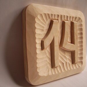 May include: A wooden plaque with the number 14 carved into it. The plaque has a decorative border.