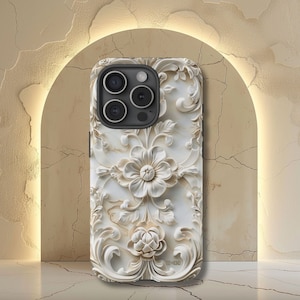May include: White iPhone case with a 3D floral design. The case has a raised, textured pattern that looks like carved marble. The camera lens is visible on the back of the case.