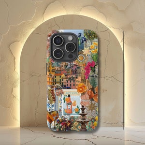 May include: A colorful phone case with a collage of images, including a cityscape, a bottle of Aperol Spritz, and a fountain. The case has a black camera lens cutout.