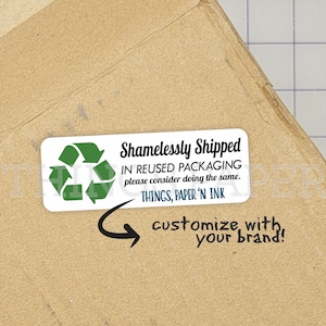 May include: A white sticker with a green recycling symbol and the text "Shamelessly Shipped in reused packaging please consider doing the same. Things, Paper 'n Ink" on a brown cardboard box. The sticker is 3.5 inches by 1.75 inches and is shown to scale on an 8.5 by 6 inch box.