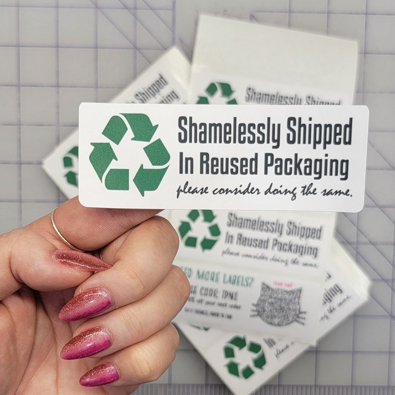 May include: A white sticker with a green recycling symbol and the text "Shamelessly Shipped In Reused Packaging please consider doing the same."