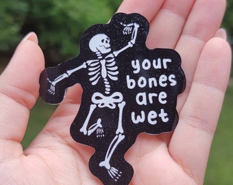 May include: A black and white sticker with a skeleton dancing and the text "your bones are wet".