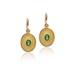May include: Gold earrings with a green gemstone set in a circular design.