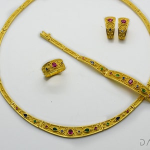 May include: A gold necklace, bracelet, ring, and earrings set with colorful gemstones. The jewelry features a detailed, ornate design.