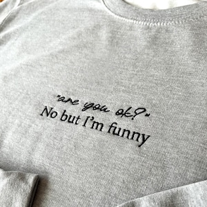 May include: Grey sweatshirt with black embroidered text that reads "are you ok? No but I'm funny."