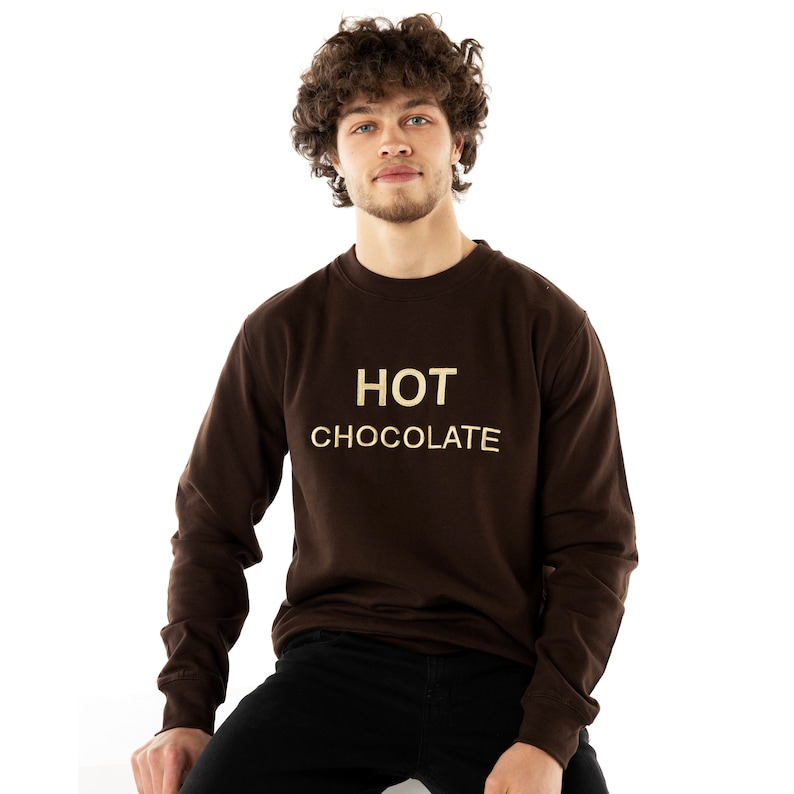 May include: A brown sweatshirt with the text "HOT CHOCOLATE" in gold lettering.