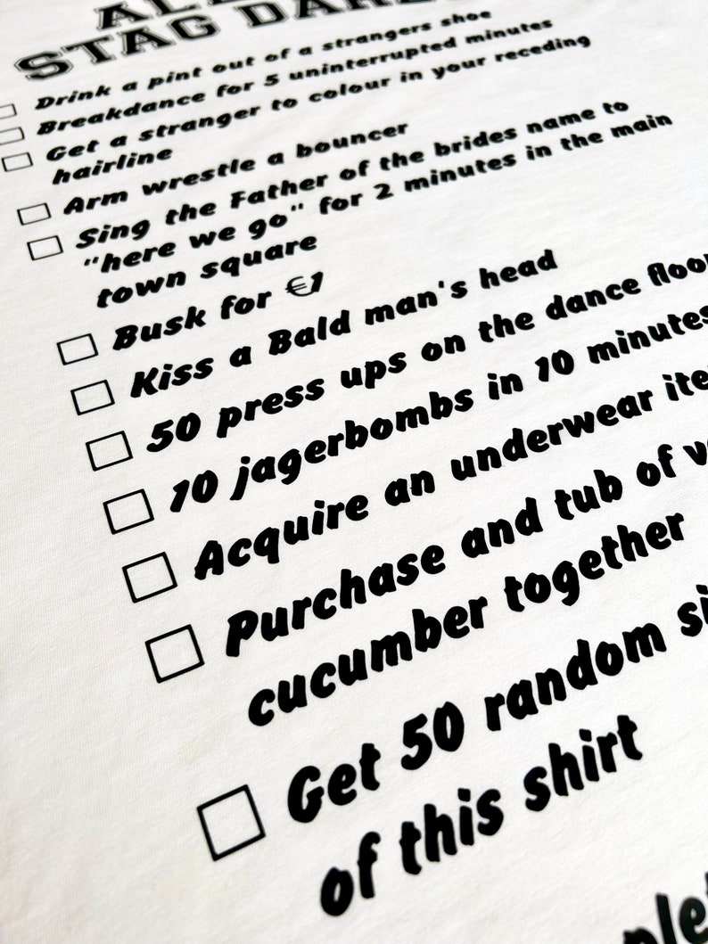 May include: A white t-shirt with a black checklist of humorous tasks, including 'Drink a pint out of a stranger's shoe' and 'Get 50 randoms of this shirt'. The text is in a bold, handwritten style.