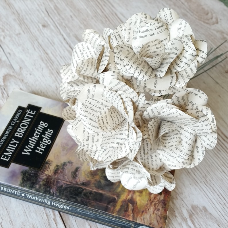 May include: A bouquet of paper flowers made from the pages of a book. The book is titled "Wuthering Heights" by Emily Bront&euml;.