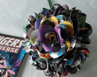 May include: A bouquet of paper flowers made from comic book pages. The flowers are arranged in a circular shape and are a mix of purple, blue, red, and yellow. The flowers are tied together with a green stem.