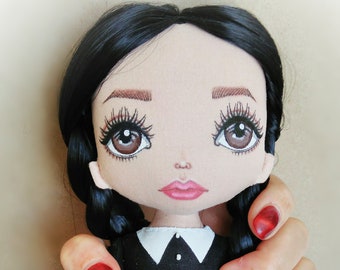May include: A handmade doll with black hair, wearing a black dress with a white collar and a black tulle skirt. The doll is holding a smaller doll in her arms. The doll's eyes are brown and she has red lipstick. The doll is being held by a hand with red nail polish. The image includes the text "NezabudkaDolls".