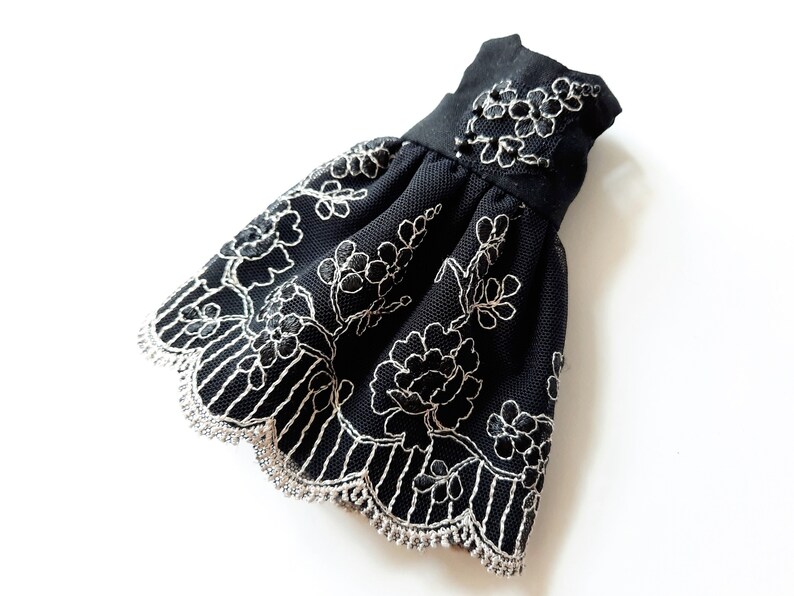 May include: A black tulle dress with silver floral embroidery and a scalloped lace trim.