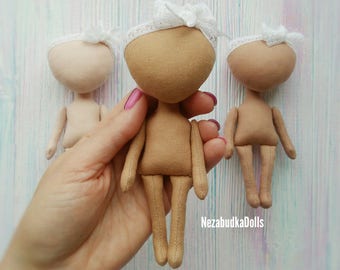 May include: Three handmade fabric dolls with white lace headbands. The dolls are beige and have no facial features. The dolls are standing on a light wood surface.