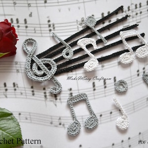 May include: Crochet pattern for musical notes and a treble clef. The pattern includes instructions for making both white and gray notes. The pattern is available as a PDF e-book. "Make It Easy Craftroom" is written on the sheet music.
