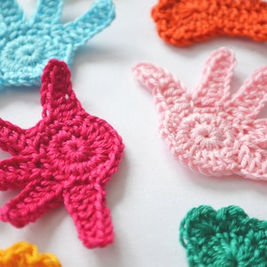 Puede incluir: Cinco formas de mano de ganchillo en diferentes colores: rosa, azul, verde, naranja y rojo. Las formas de mano son todas del mismo tama&ntilde;o y tienen un dise&ntilde;o simple.