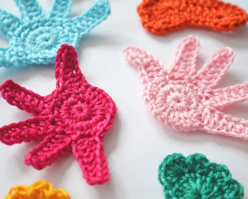 Puede incluir: Cinco formas de mano de ganchillo en diferentes colores: rosa, azul, verde, naranja y rojo. Las formas de mano son todas del mismo tama&ntilde;o y tienen un dise&ntilde;o simple.