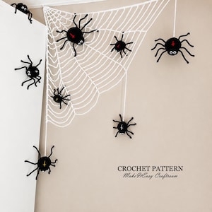 May include: A white crocheted spider web hanging in a corner with seven black crocheted spiders attached to the web and the wall. Each spider features white eyes and a small cross symbol in red, yellow, or white on its back. Text reads CROCHET PATTERN MakeItEasy Craftroom.