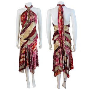 May include: A sleeveless halter-neck dress featuring a patchwork design with various floral, animal print, and geometric patterns in shades of deep red, burgundy, gold, and cream. The dress has a flared, asymmetrical hemline and a long tie at the neck.