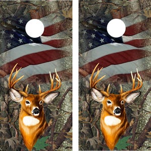 May include: Two cornhole boards with a camouflage background and an American flag design. A whitetail deer head is featured in the center of each board.