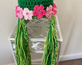 May include: Green crocheted hat with pink flowers and long green yarn braids.