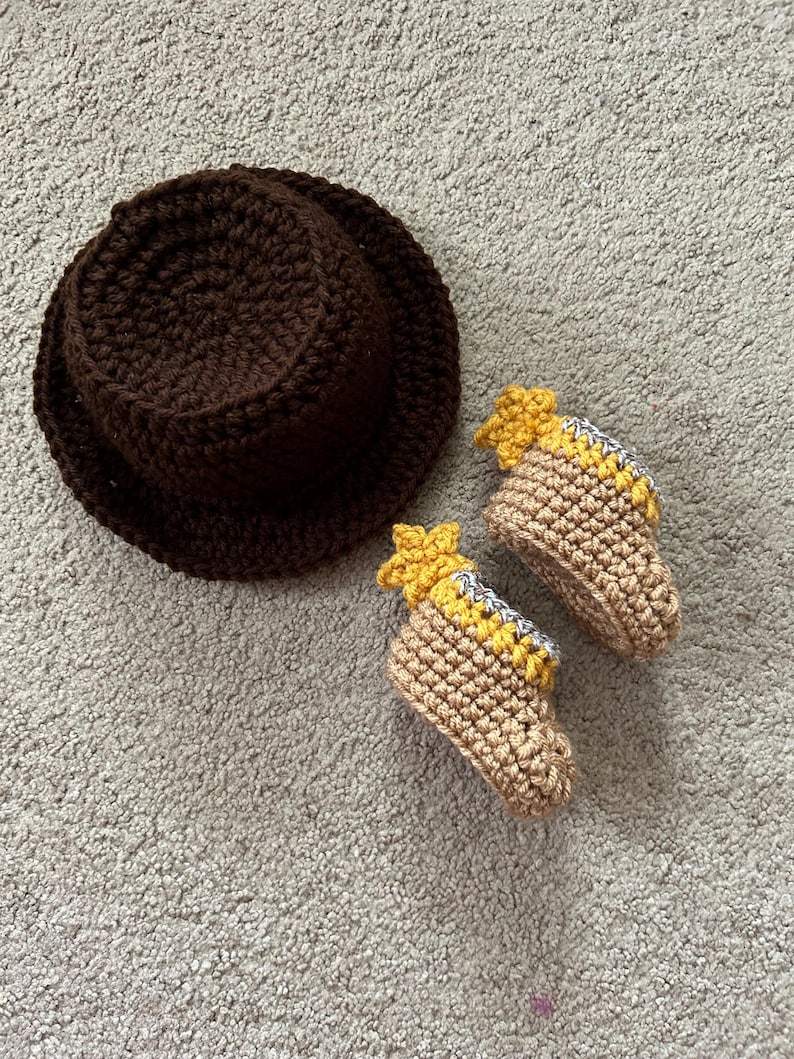May include: A brown crocheted hat and a pair of tan crocheted baby booties with yellow star accents.