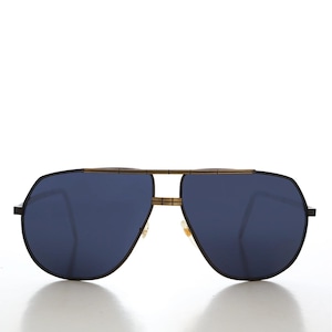 May include: Aviator sunglasses featuring a black frame and dark blue lenses. The sunglasses have a gold-coloured bridge and nose pads. The design is a classic, retro style.