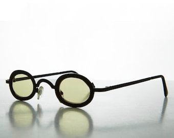 May include: Black oval-shaped sunglasses with yellow-tinted lenses. The frames are thin and the bridge has a small nose piece. The arms extend straight back and then curve down. The glasses are set against a light background.