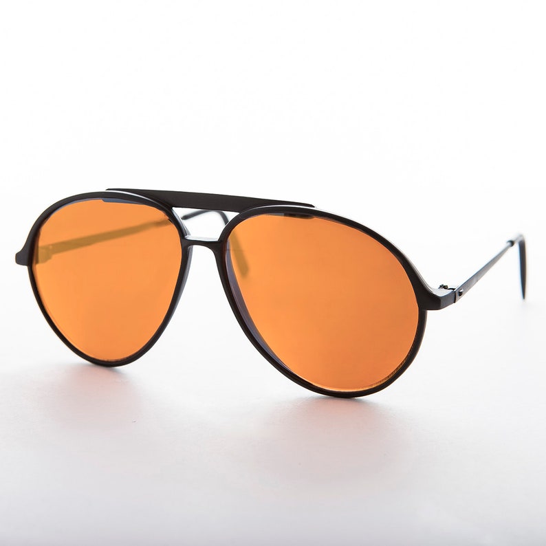 K&ouml;nnte beinhalten: Schwarze Aviator-Sonnenbrille mit orangenen Gl&auml;sern und einem Metallrahmen.