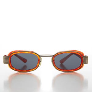 Puede incluir: Gafas de sol ovaladas de color naranja y marrón con montura de metal.