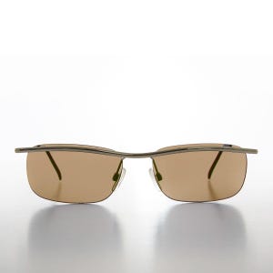 May include: Rimless sunglasses featuring a thin, metallic brow bar that extends across the top of the lenses. The lenses are tinted in a warm brown hue, and the frame includes adjustable nose pads and slender temples for a lightweight construction.