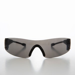Könnte beinhalten: Schwarze Wrap-Around-Sonnenbrille mit grauen Gläsern. Die Sonnenbrille hat ein elegantes, modernes Design.