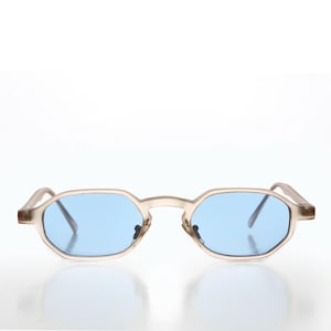 May include: A pair of vintage-style sunglasses with a light brown frame and light blue lenses. The lenses have an octagonal shape. The sunglasses are set against a white background.