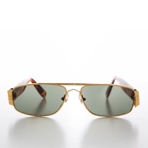May include: Gold-framed sunglasses with green lenses. The sunglasses have a rectangular shape with a double bridge and tortoise-shell arms. The frame is a bright gold color.