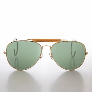 May include: Gold aviator sunglasses with green lenses and a brown bridge.