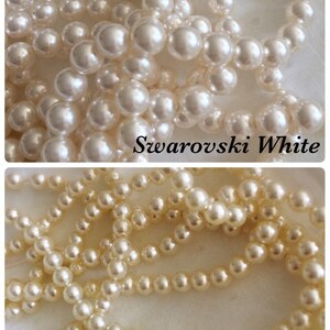 May include: Two strands of white pearl beads, one strand is labeled "Swarovski White" and the other is labeled "Swarovski Cream".